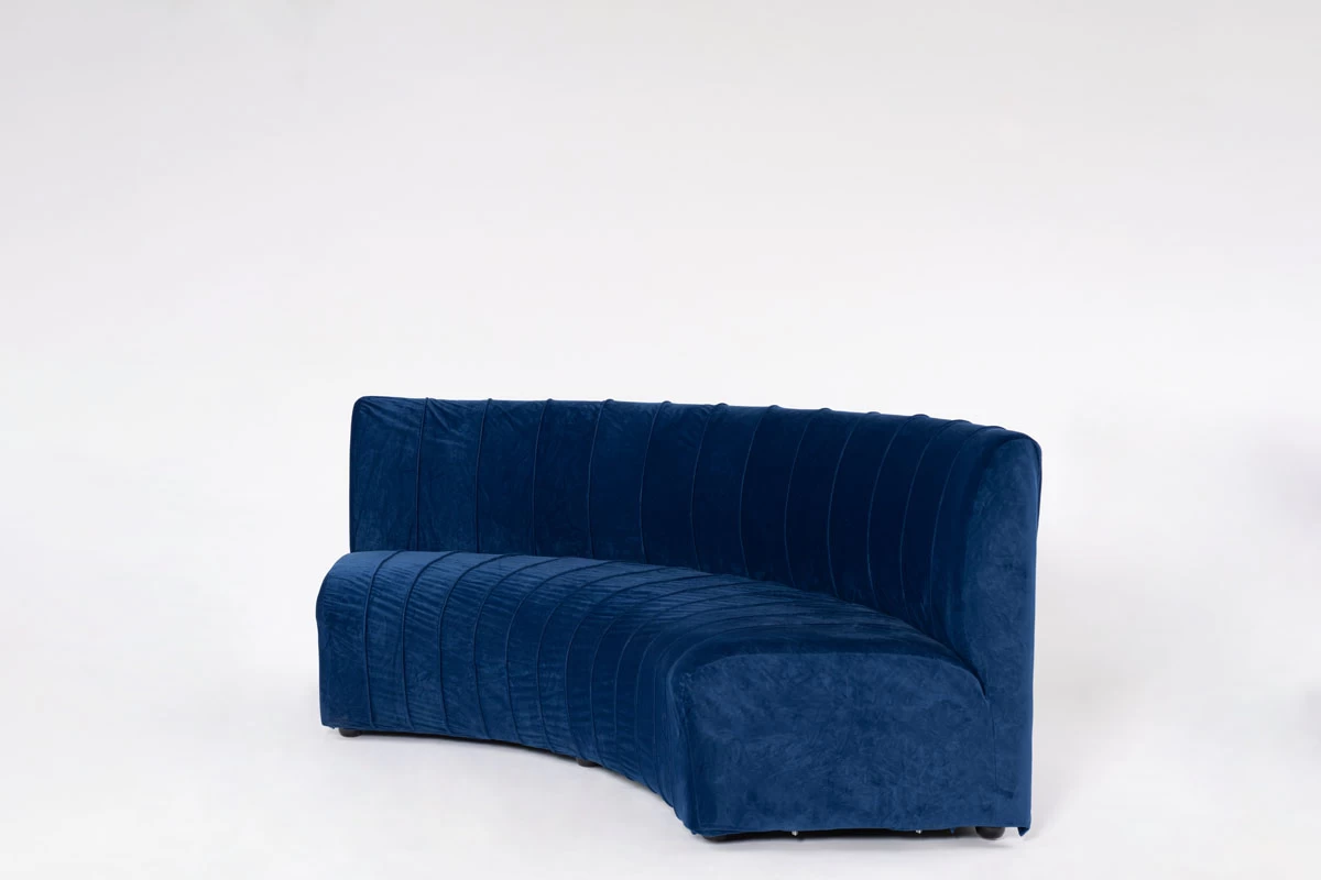 ספה מעוגלת מרופדת קטיפה כחולה, מודרנית ונוחה. ריפוד עם תפרים אנכיים. צילום סטודיו מקצועי של רהיט
