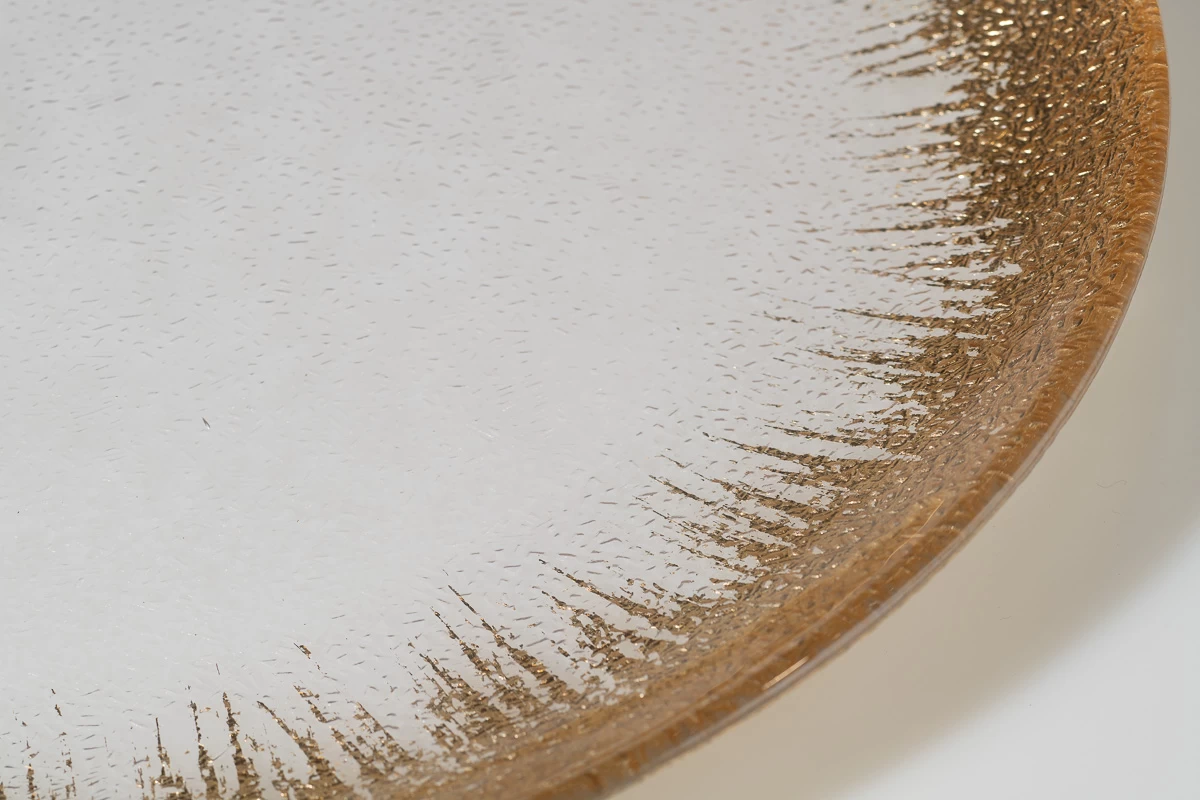 צילום תקריב -צלחת זכוכית דקורטיבית עם שוליים מוזהבים, צילום סטודיו מקצועי. מרקם עדין וייחודי, מושלם לעיצוב שולחן חגיגי או כפריט נוי יוקרתי.